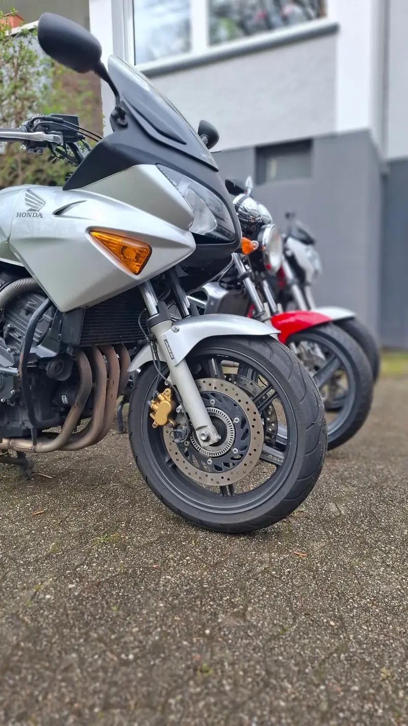 Die silberne Honda CBF600 der Fahrschule Steinhoff von schräg vorn, dahinter die beiden anderen Schulmotorräder